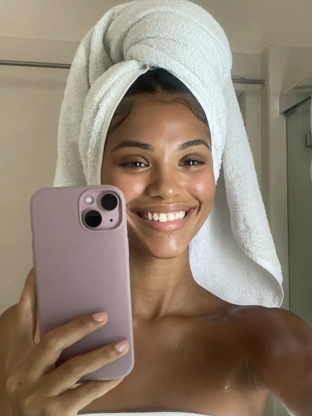 Selfie no espelho: jovem morena sorrindo com toalha na cabeça depois da rotina